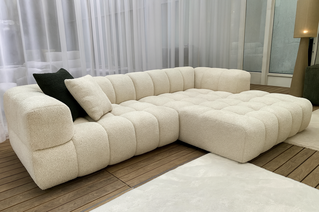 Canapé d’angle beige arrondi matelassé Vida exposé en magasin Souffle d’Intérieur – design contemporain et confort haut de gamme