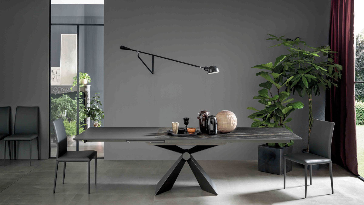 Table extensible Sintesi ouverte avec sa rallonge, pied central en métal, dans une salle à manger