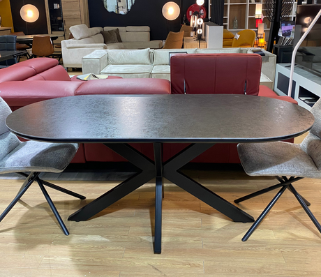 table ovale céramique grise pieds central métal noir dans le magasin devan un canapé d'angle en cuir