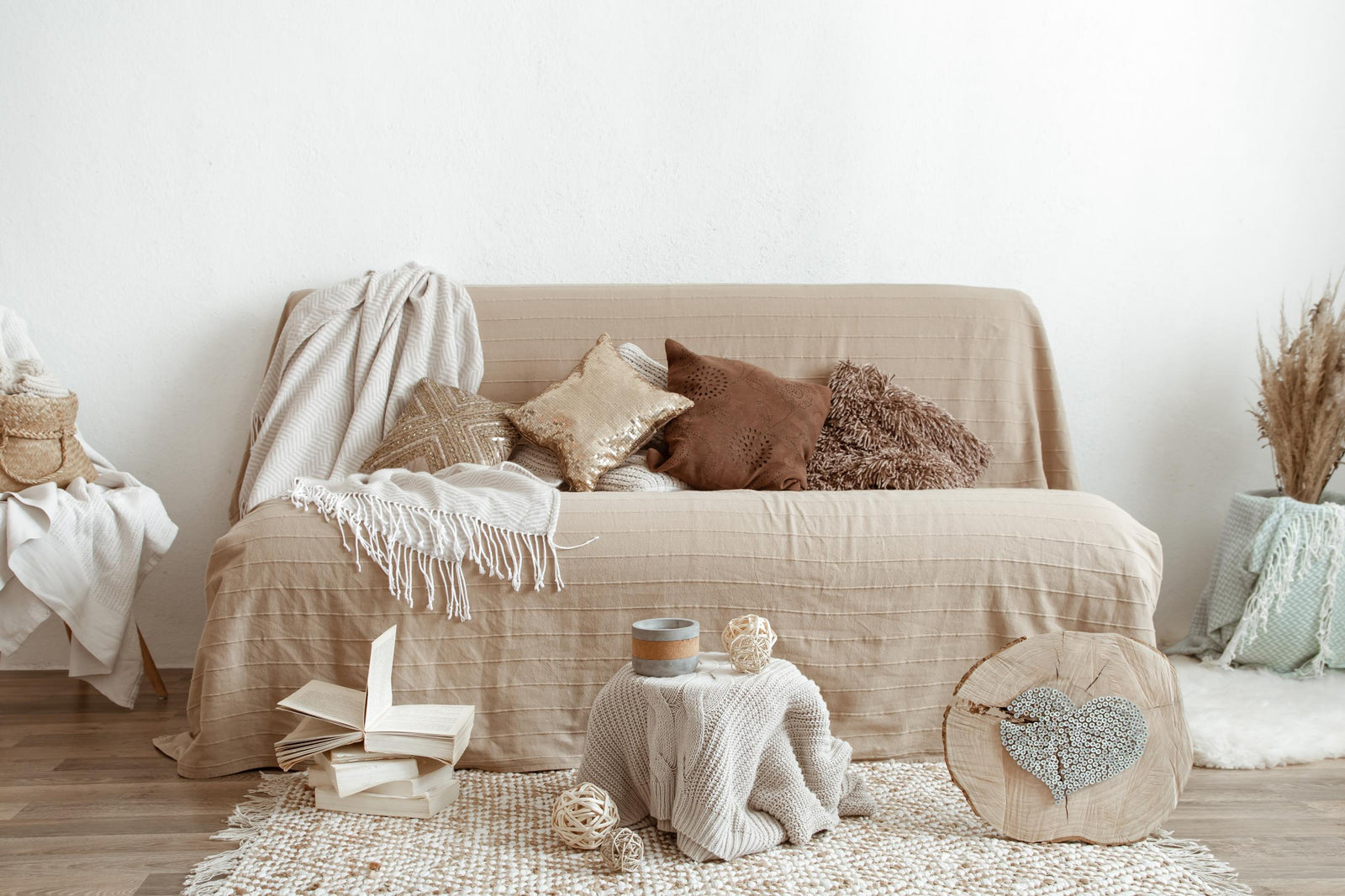 canapé beige recouvert d’un plaid, décoré de coussins moelleux et d’éléments en bois et en fibres naturelles
