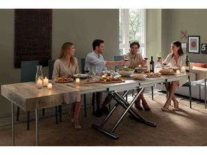 Table basse Assista relevable en position haute avec convives partageant un repas dans un salon contemporain